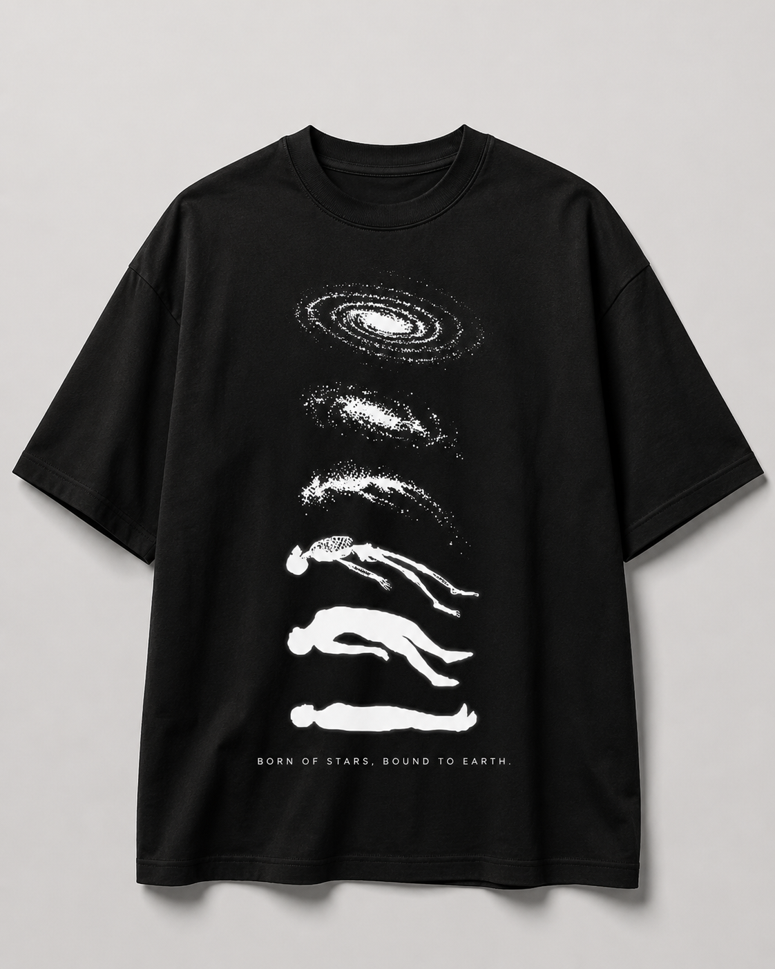 A black short-sleeve crewneck t-shirt with a white graphic print of stacked galaxies and human silhouettes, with the text 'BORN OF STARS, BOUND TO EARTH' printed at the bottom, shown against a neutral gray background.
