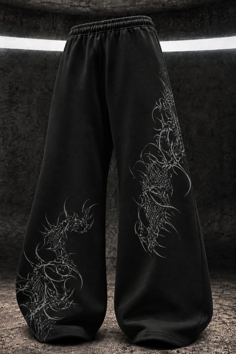 Black wide-leg sweatpants with intricate white dragon illustrations printed on both legs, displayed against a dark textured studio background.